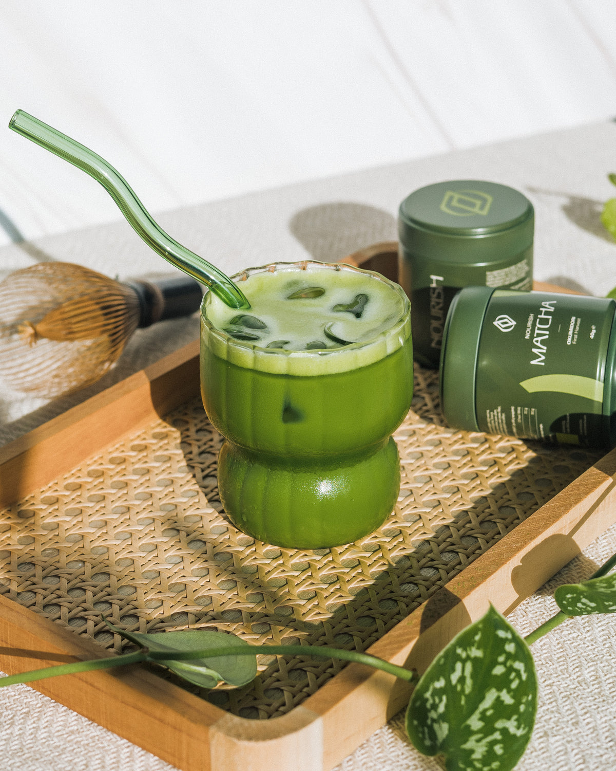 Студено матча лате със стъклена сламка, часен и кутии матча NOURISH
